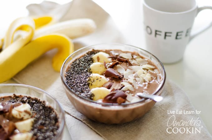 A close up of a mocha smoothie bowl topped with sliced banana, shaved chocolate and sliced almonds.