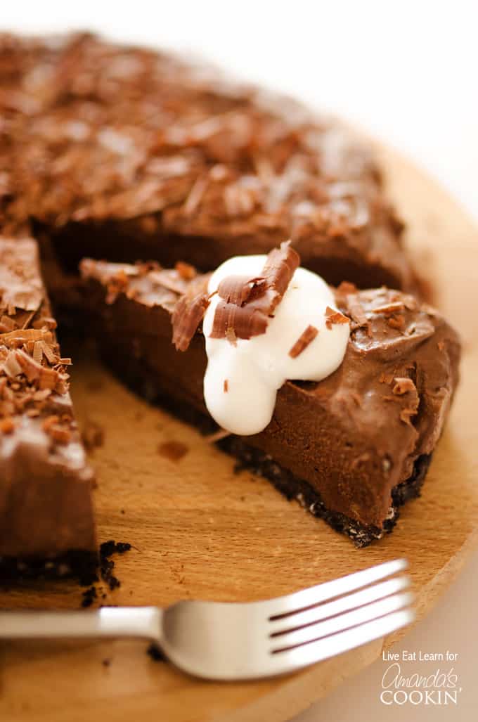 A close up of an avocado chocolate mousse cake slice next to the rest of the cake.