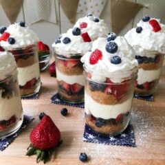 mason jars layered with berries, cake, and whipped cream