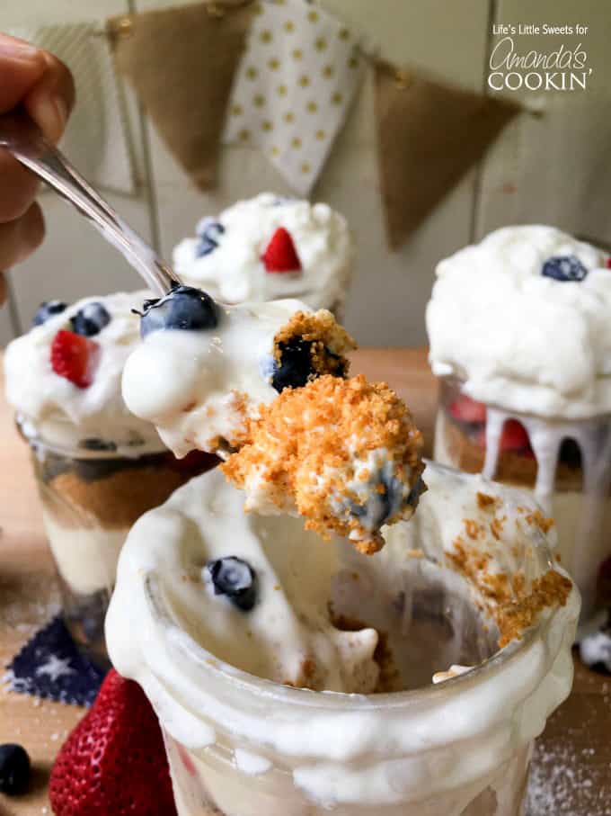 A close up of spoonful of no bake berry cheesecake trifles with more in the background.