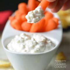 A close up of a carrot dipped in skinny French onion dip with dip and carrots in a serving dish in the background.