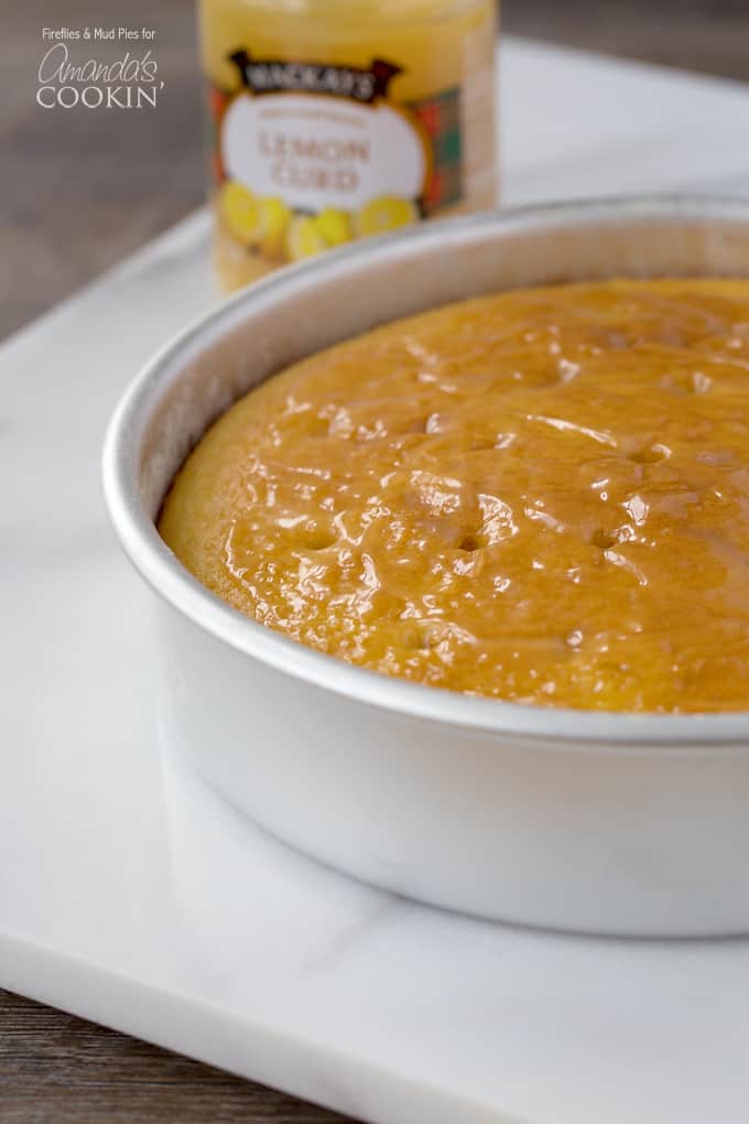 A close up photo of a fresh baked lemon curd poke cake resting in a cake pan.