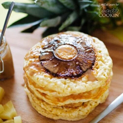 A close up photo of a stack of pineapple pancakes on a wooden cutting board.