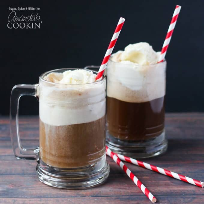 A close up photo of two root beer float cocktails in clear mugs served with red and white stripped straws.