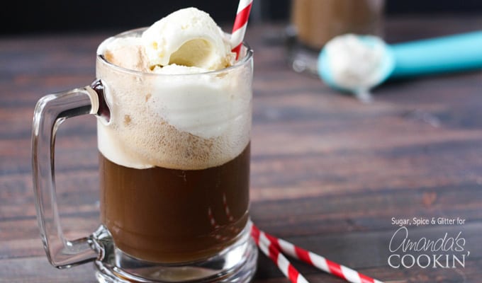 A photo of a root beer float cocktail in a clear mug served with a red and white striped straw.