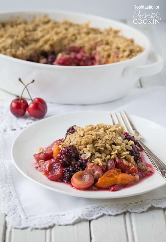 Summer fruit crisp on a white plate with a fork on the side.