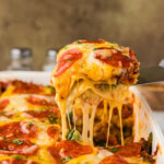 spatula lifting a piece of pizza lasagna from the pan