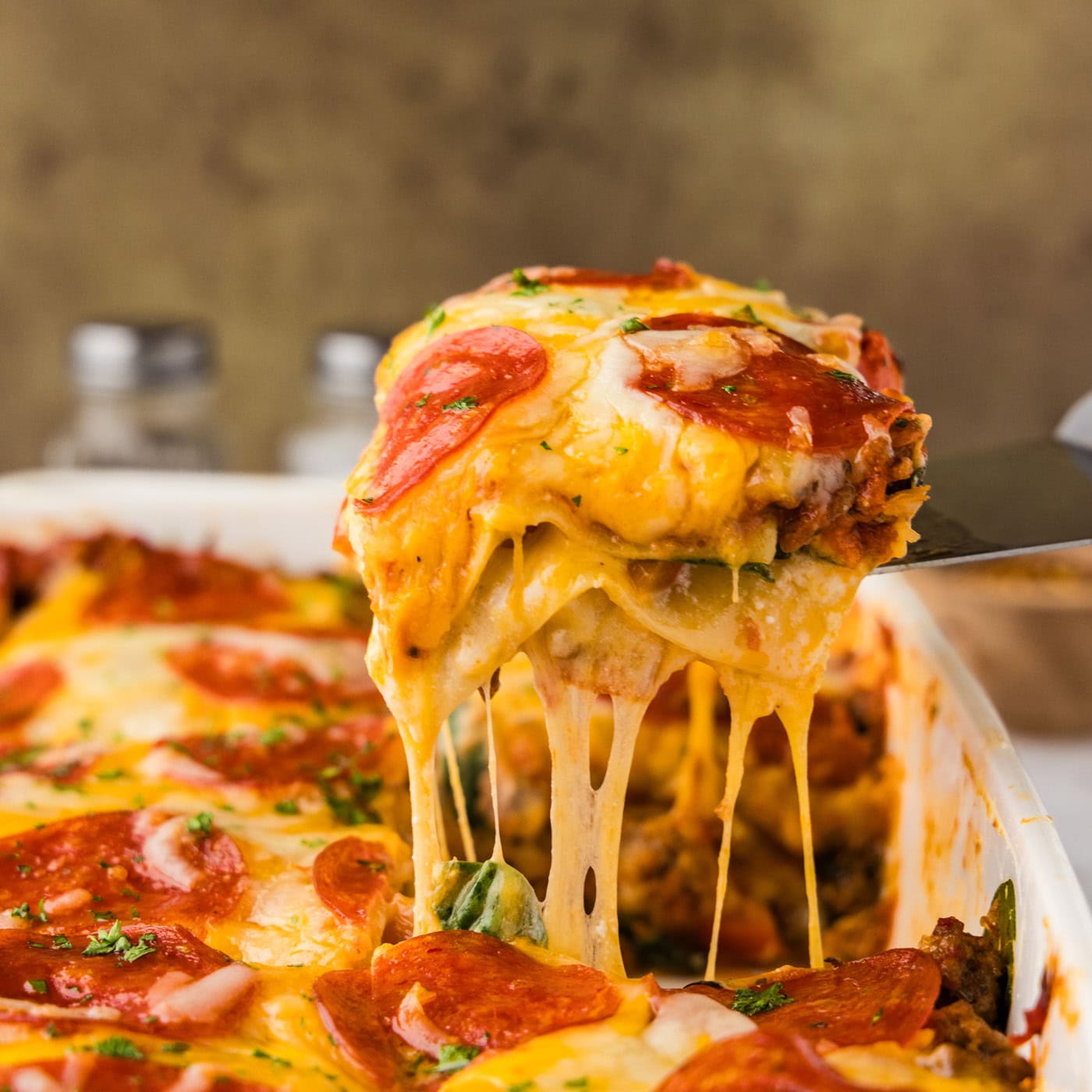 spatula lifting a piece of pizza lasagna from the pan