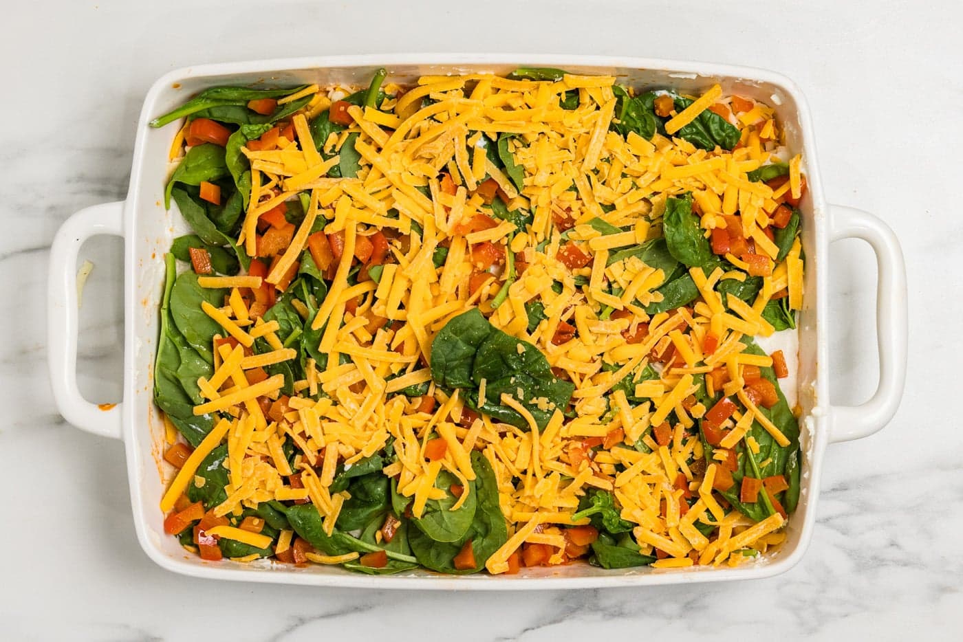 cheese spread over vegetable layer in baking dish