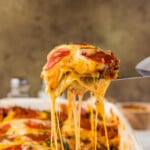 spatula lifting pizza lasagna with a cheese pull