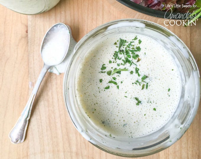 A close up of a bowl of buttermilk ranch with a spoon on the side.