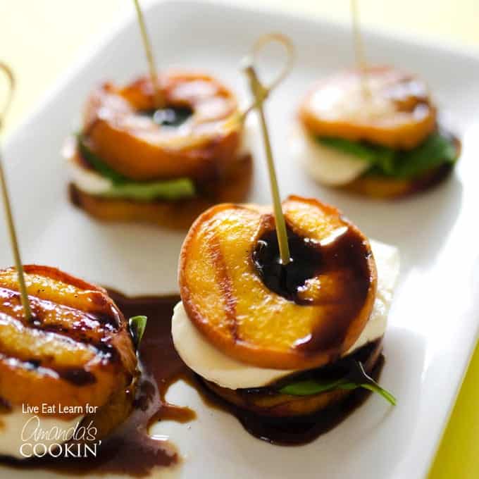 A close up of grilled peach caprese on a white platter. 