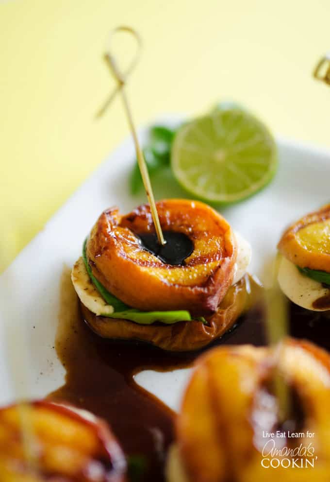A close up of grilled peach caprese on a white platter with a lime wheel in the background.