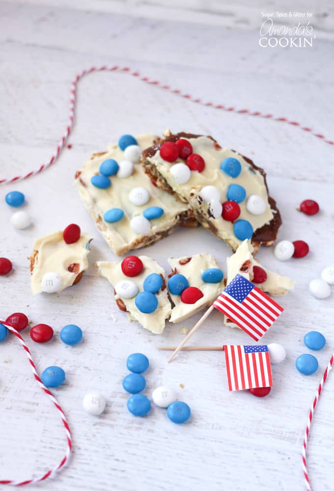 An overhead photo of patriotic candy bark with red white and blue M&Ms and American flags in the background.