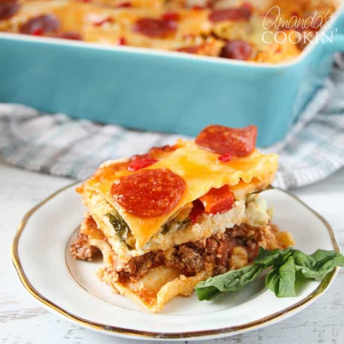 A close up of pizza lasagna on a white and gold plate.