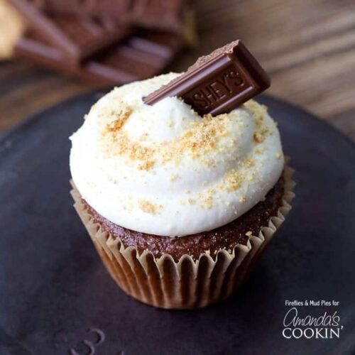 A close up of a s'mores cupcake topped with a Hershey bar piece.