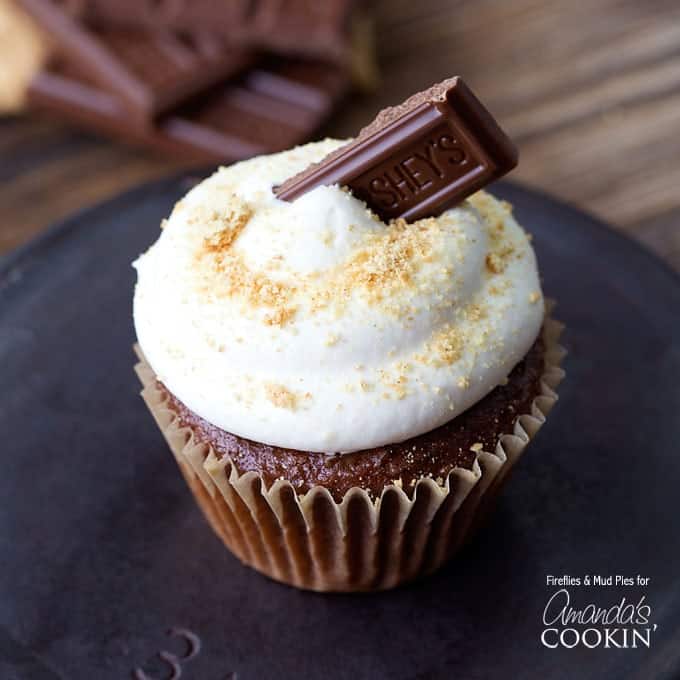 A close up of a s\'mores cupcake topped with a Hershey bar piece. 