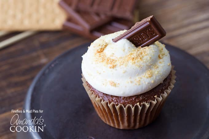 A close up of a s\'mores cupcake topped with a Hershey bar piece. 