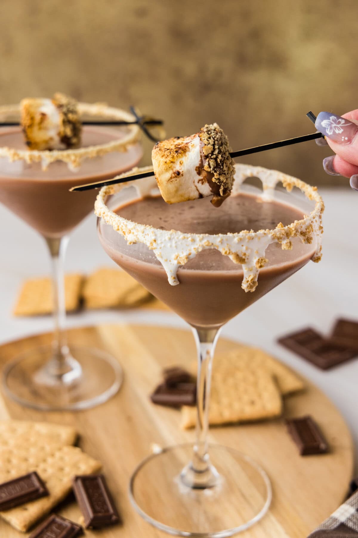 lifting roasted marshmallow garnish off of a S'mores Martini