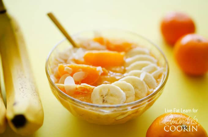 A close up of an almond orange smoothie bowl topped with mandarine oranges and sliced banana.