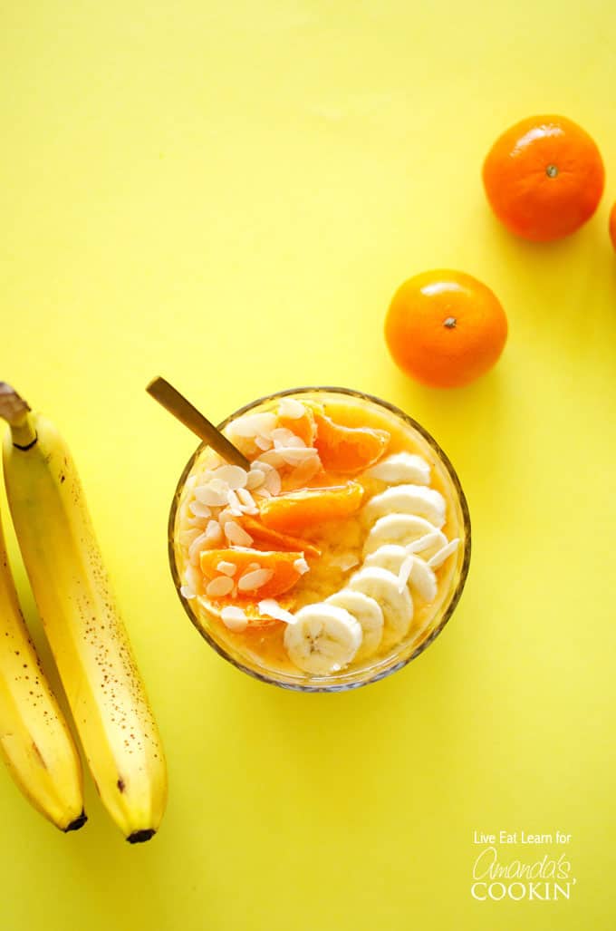 An overhead of an almond orange smoothie bowl topped with mandarine oranges and sliced banana.