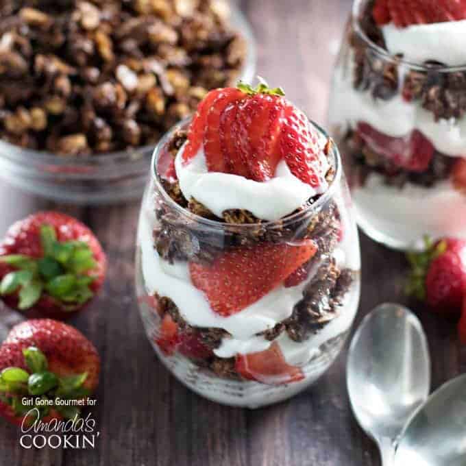 A close up photo of breakfast parfaits with strawberries and dark chocolate granola.