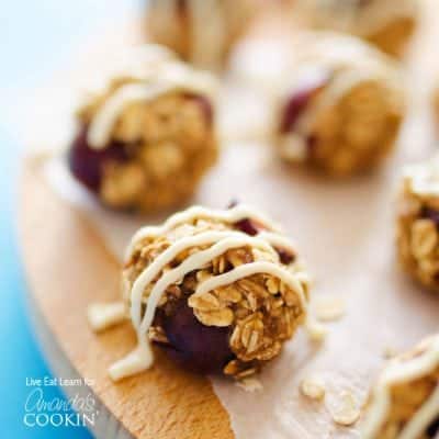 A close up photo of cherry cheesecake energy balls drizzled with cream cheese frosting.