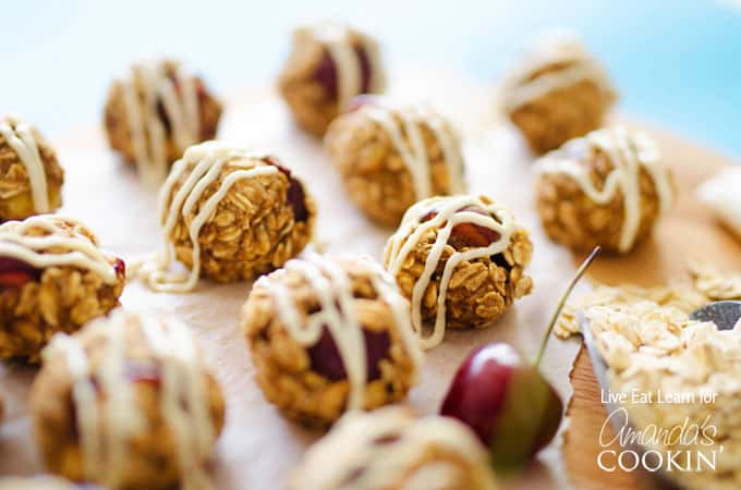 A close up photo of cherry cheesecake energy balls drizzled with cream cheese frosting.