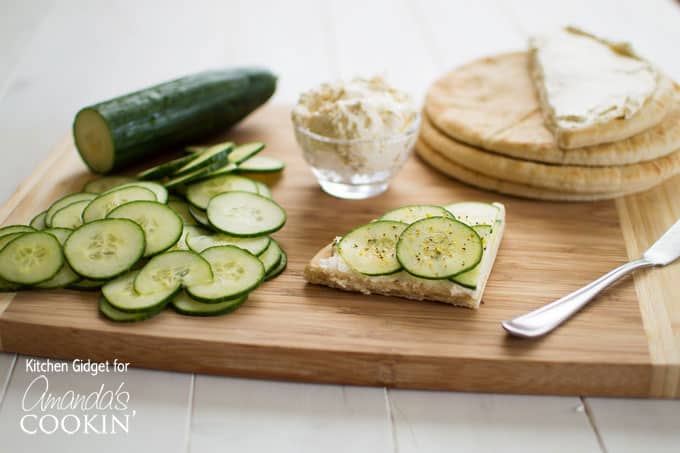 cucumbers, pita, and spread with cucumber sandwich on a wooden cutting board