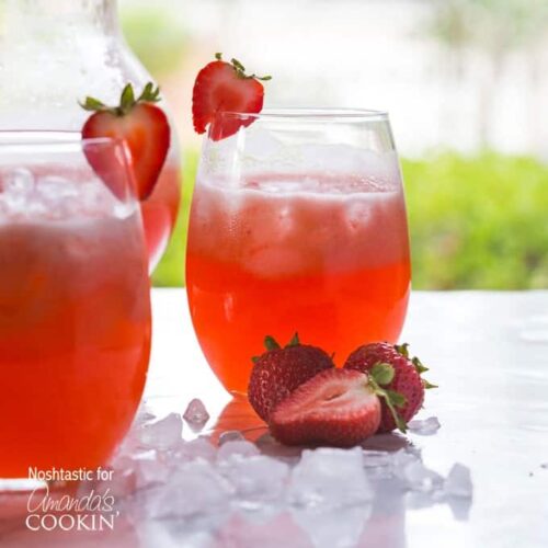 Two short glasses filled with strawberry lemonade served with sliced strawberries on the rim of the glass and on the side.