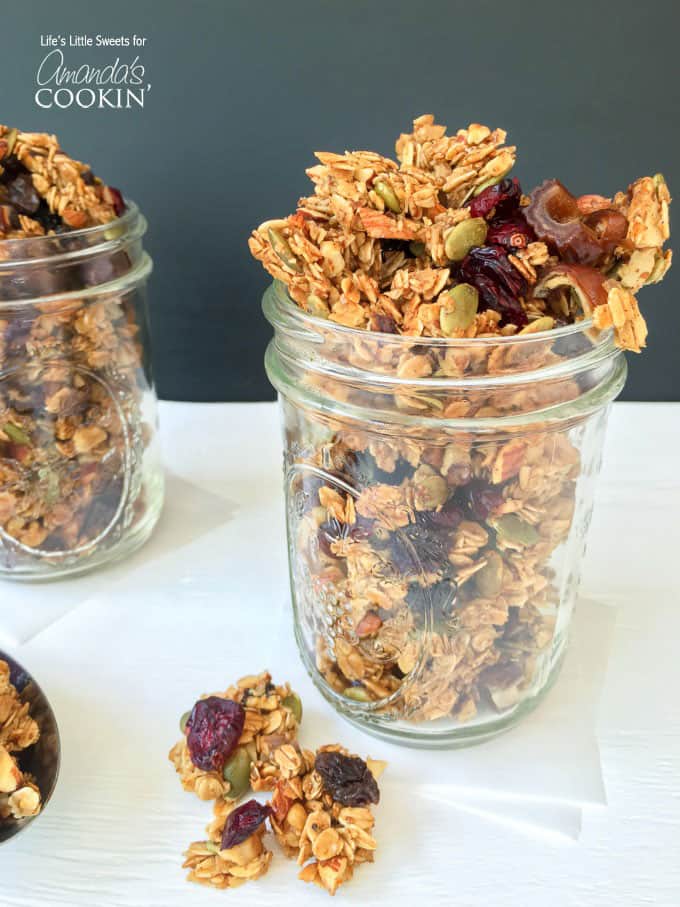 A close up photo of autumn harvest fruit and nut granola in a mason jar.