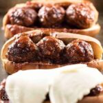 A close up photo of three slow cooker BBQ meatball subs, one topped with provolone cheese.