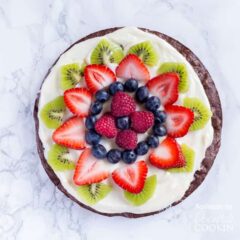 An overhead photo of fruit cut up on top of a brownie pizza.