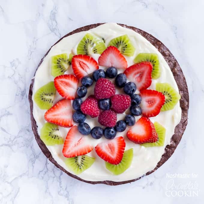 An overhead of cut up fruit on top of a brownie pizza.