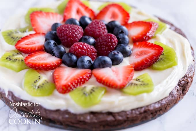 A close up of cut up fruit on top of a brownie pizza.