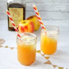 Two mason jars filled with apple pie cocktails and served with a red and white straw.