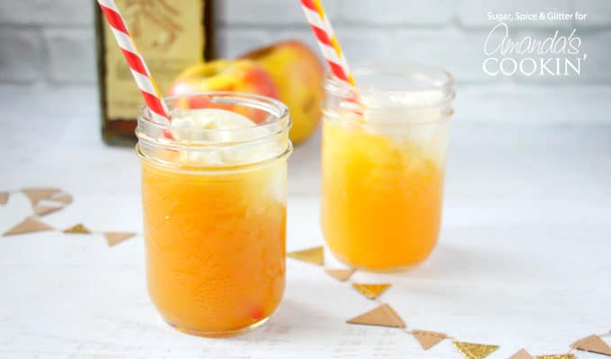 A close up of two mason jars filled with apple pie cocktails and served with a red and white straw.