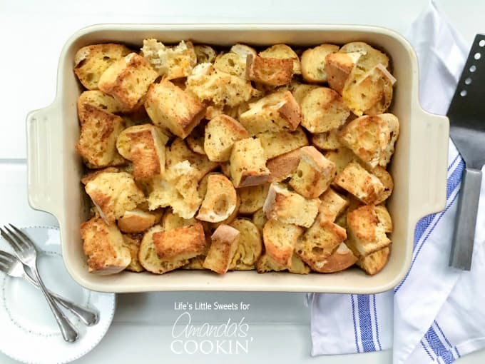 An overhead of a 9x13 baking pan filled with cut up french baguettes. 