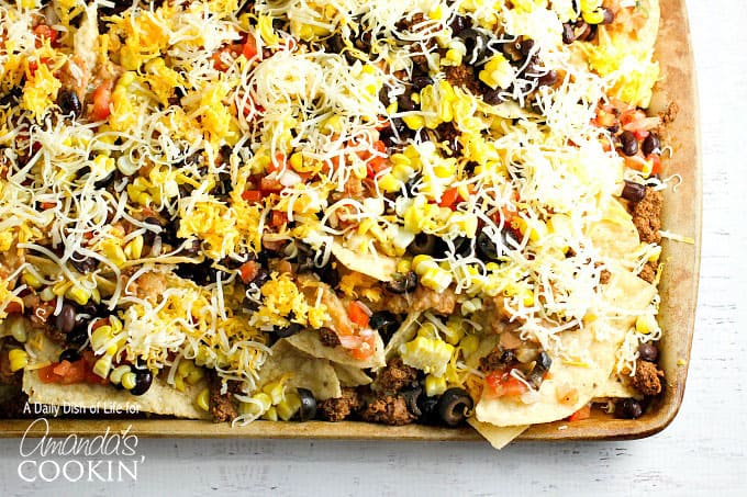 A close up overhead  of loaded nachos on a baking sheet.