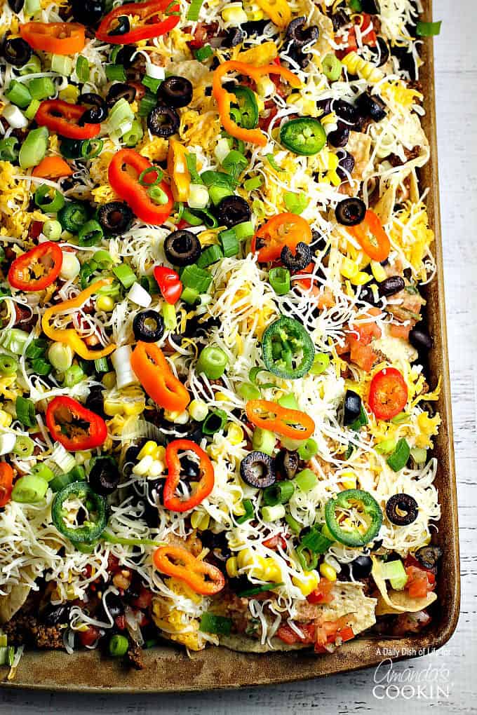 An overhead of loaded nachos on a baking sheet.