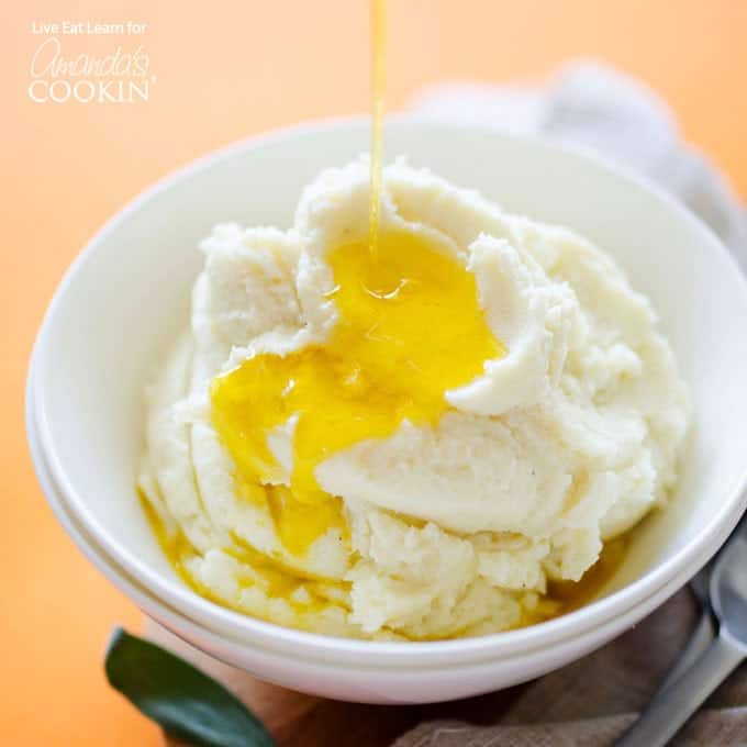 A white bowl filled with mashed cauliflower and melted butter on top.