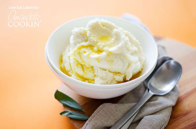 A white bowl filled with mashed cauliflower and melted butter on top.