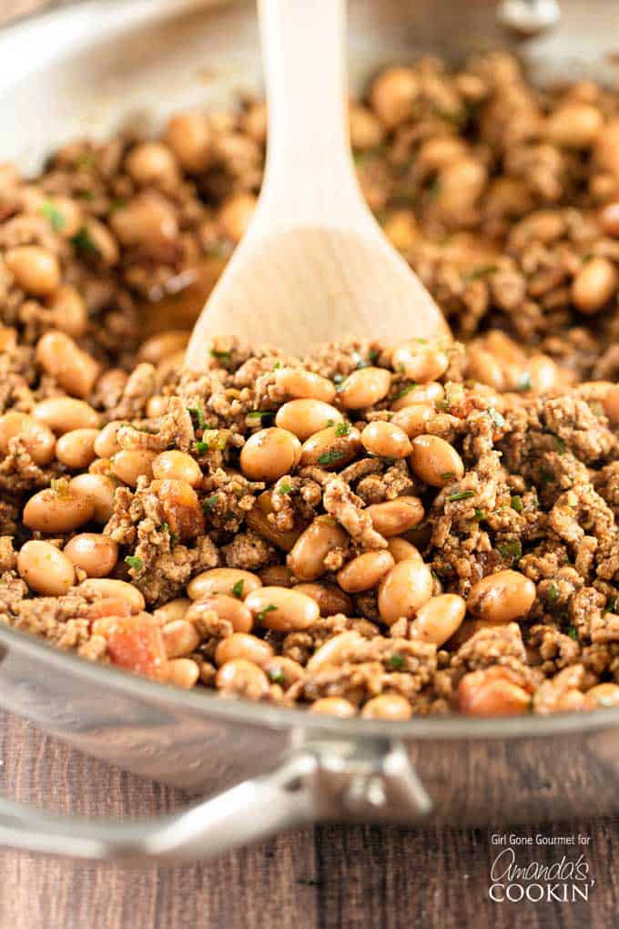 A close up photo of a clear bowl filled with beef and bean taco meat.