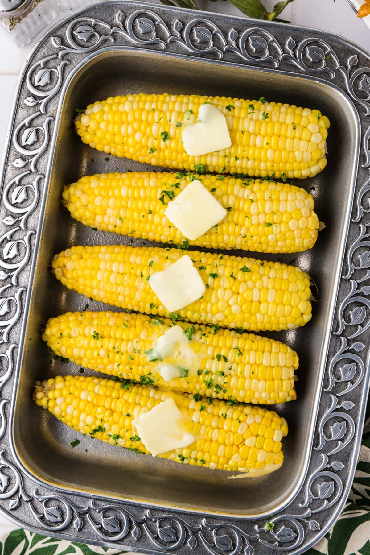 ovehead photo of corn on the cob with butter in serving tray