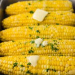 corn on the cob that was made in the crockpot sitting in a serving tray