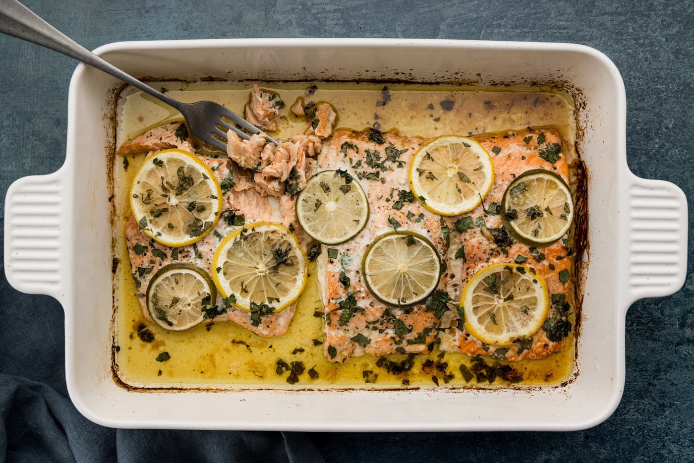 baked salmon in a pan with fork pulling it apart