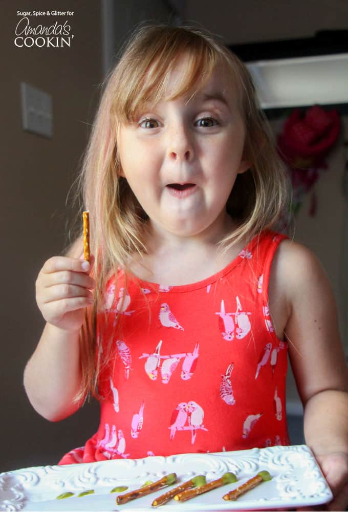 A little girl holding a pretzel stick.