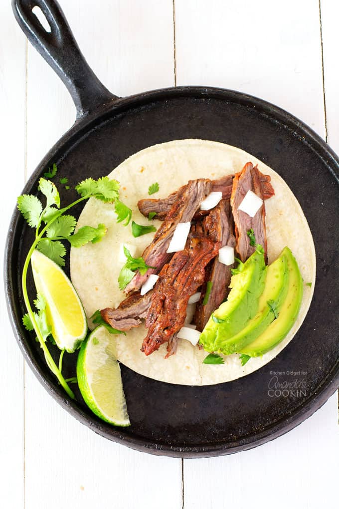 carne asada on skillet with avocado and lime