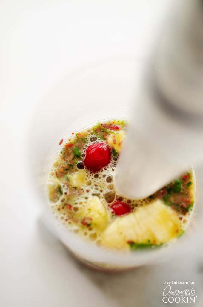 A close up photo of a cranberry smoothie being blended with an immersion blender.