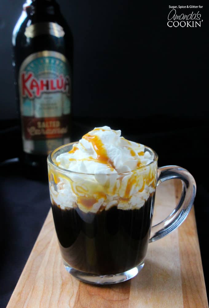 A salted caramel coffee cocktail in a clear mug with whipped cream and drizzled caramel on top.